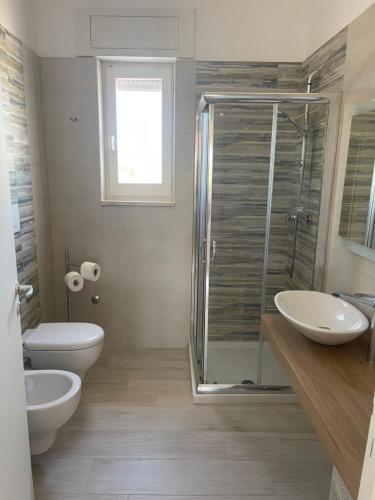 een badkamer met een douche, een toilet en een wastafel bij SINE TEMPORE Beach Holiday Home in Maruggio