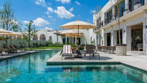 a swimming pool with chairs and umbrellas next to a building at Casa Itzae La Luminaria Dog Friendly in San Miguel de Allende