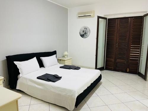 um quarto com uma cama grande com lençóis brancos e detalhes em preto em IL QUADRIFOGLIO intero appartamento centro città em Villa San Giovanni