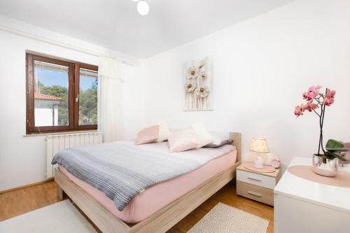 biała sypialnia z łóżkiem i oknem w obiekcie Apartment Jasna Punat w mieście Punat