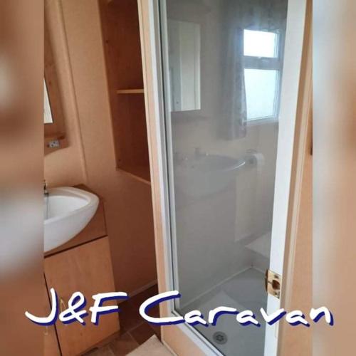 eine Dusche mit Glastür im Bad in der Unterkunft J & F caravan in Skegness