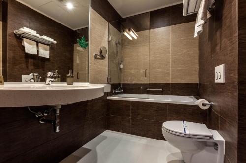 a bathroom with a sink and a toilet and a tub at Rius Hotel Lviv in Lviv