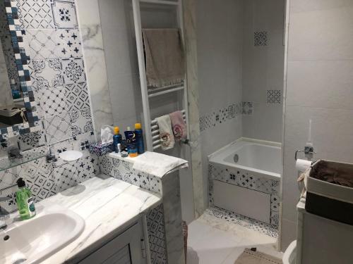 a white bathroom with a sink and a tub at Alcasar Beach 3 rooms apartment in Sousse