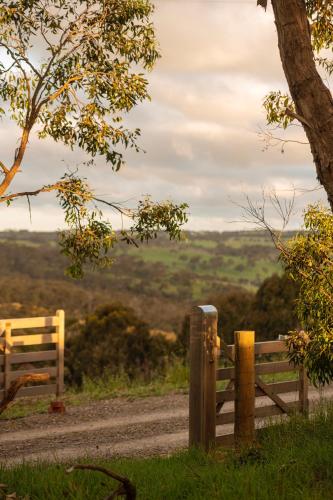 a wooden fence on a dirt road near a field at Old Coach Road Estate in Hindmarsh Valley