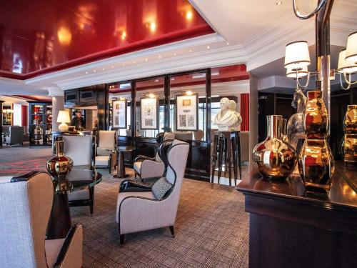 a lobby with a bar with chairs and a bust of a woman at Park Hôtel Grenoble - MGallery in Grenoble
