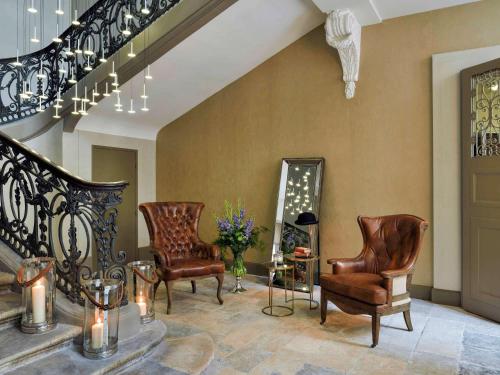 a living room with two chairs and a staircase at La Cour des Consuls Hotel and Spa Toulouse - MGallery in Toulouse