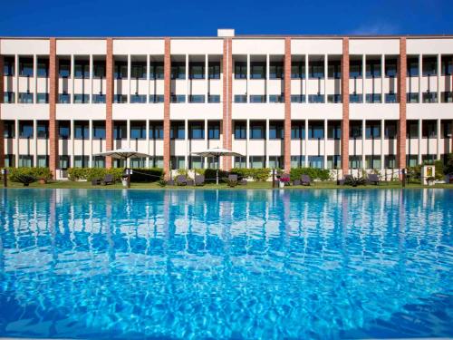 a building with a large pool of water in front of it at Mercure Leonardo da Vinci Rome Airport in Fiumicino