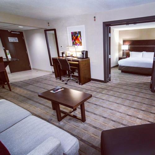 a hotel room with a bed and a desk and a living room at Holiday Inn Charlotte Airport by IHG in Charlotte
