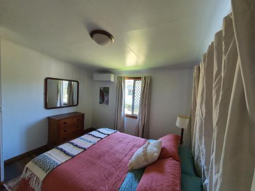 a small bedroom with a bed and a mirror at Cottage on Herbert in Ravenshoe