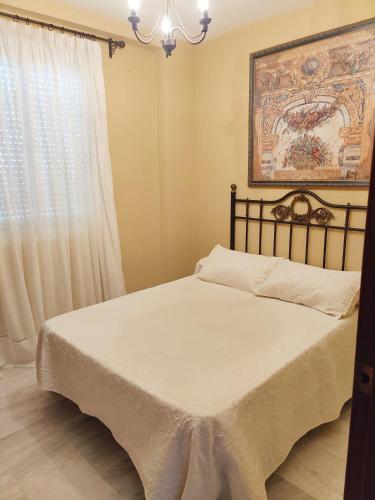 a bedroom with a bed with a painting on the wall at Apartamento Nao Victoria in Sanlúcar de Barrameda