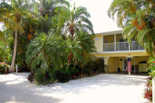 ein gelbes Haus mit Palmen davor in der Unterkunft Siesta Palms By the Beach in Sarasota