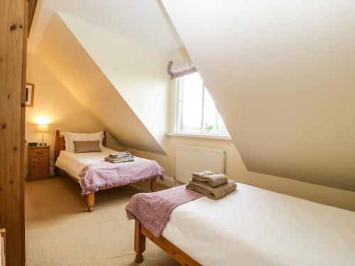 een zolderslaapkamer met twee bedden en een raam bij Belview Cottage in Sturminster Newton