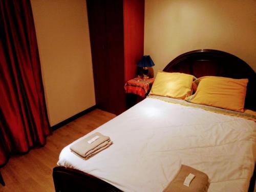 a bedroom with a large bed with white sheets and yellow pillows at Casa de Huéspedes Tu Parada en Cuenca in Cuenca