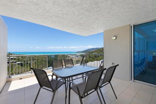 a table and chairs on a balcony with a view of the ocean at Azure Sea Whitsunday Resort in Airlie Beach