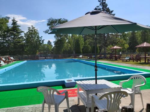 einen Tisch mit einem Sonnenschirm neben einem Pool in der Unterkunft Auberge La Coudriere (Cool Hotel) in L'Isle-aux-Coudres