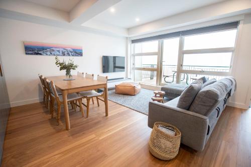 a living room with a table and a couch and a dining room at Mt Buller Chalet Hotel & Suites in Mount Buller