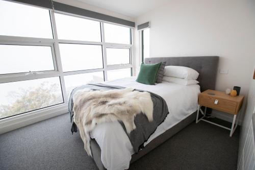 a bedroom with a bed and a large window at Mt Buller Chalet Hotel & Suites in Mount Buller
