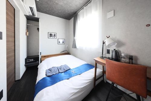 a bedroom with a bed and a desk and a window at Hotel Potmum Sapporo in Sapporo