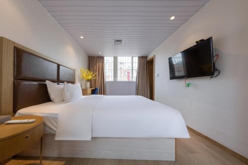 a bedroom with a white bed and a tv on the wall at Ibis Styles XM Zhongshan Hotel in Xiamen