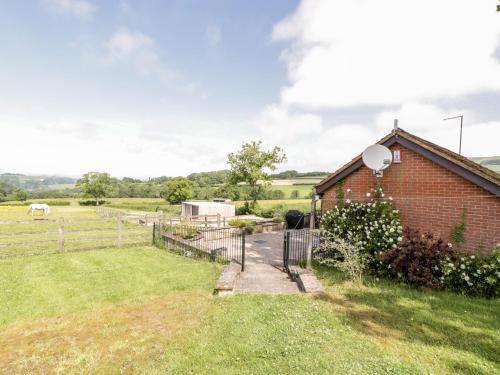 a brick house with a fence and a field at The Stables in Taunton
