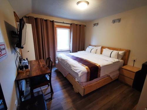 Schlafzimmer mit einem Bett, einem Schreibtisch und einem Fenster in der Unterkunft Riverfront Estate Bed&Breakfast Banff in Banff