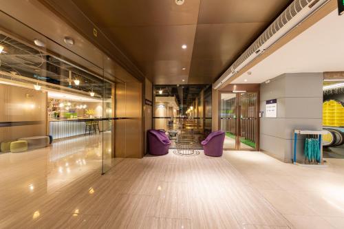 a hallway with purple chairs in a building at Ibis Styles XM Zhongshan Hotel in Xiamen