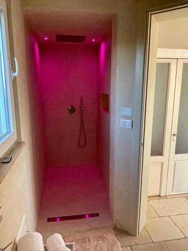 a walk in shower with pink lighting in a bathroom at MAREULIVI in Ostuni