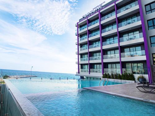 a hotel with a swimming pool next to the ocean at Fortune Saeng Chan Beach Hotel Rayong - SHA Plus in Rayong