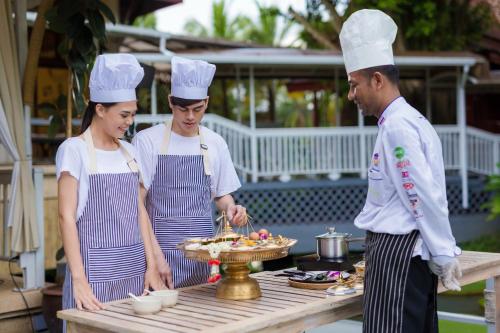 Um homem e duas mulheres em chapéus de chef a preparar comida. em Ma Doo Bua Phuket - SHA Extra Plus em Thalang