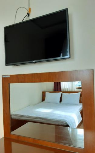 um quarto com uma cama e uma televisão de ecrã plano na parede em Que Huong Coconut Hotel em Giồng Tú Ðiền