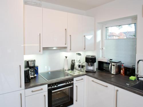 eine weiße Küche mit weißen Schränken und einem Waschbecken in der Unterkunft Landhaus Lueneburg Komfort Apartment in Lüneburg