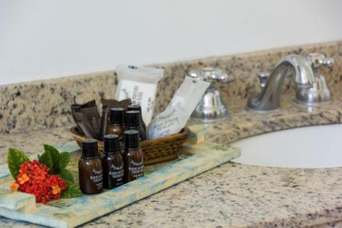 a bathroom counter with a sink with two bottles of soap at Hotel Fazenda Colina in Ouro Fino