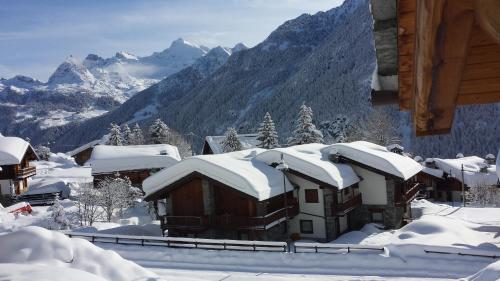 a house covered in snow with mountains in the background at Family Apartments Le Chalet in Champoluc