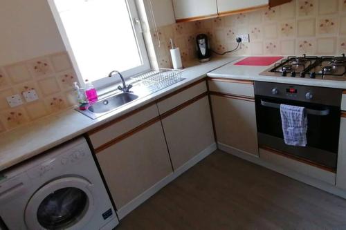 a kitchen with a sink and a washing machine at Faodail, 1 Bed Studio apartment at Ravenscraig Castle and Park in Fife