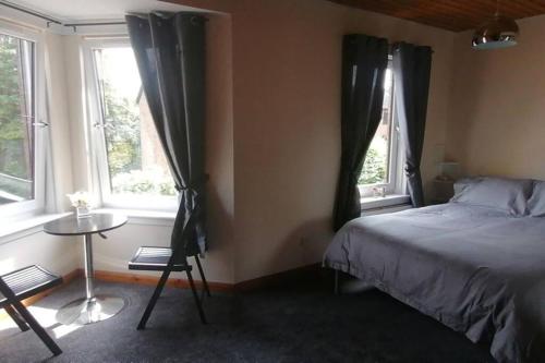 a bedroom with a bed and a table and two windows at Faodail, 1 Bed Studio apartment at Ravenscraig Castle and Park in Fife
