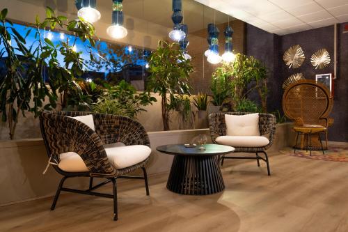 a lobby with chairs and a table and plants at Aemilia Hotel Bologna in Bologna