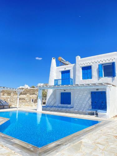 uma casa branca com uma piscina em frente em Blue Harmony Suites of Mykonos em Míconos