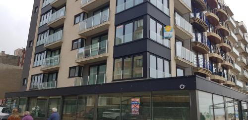 a tall building with people walking in front of it at Koksijde Zeedijk La Digue 101 appartement met garage - frontaal zeezicht - adult only in Koksijde