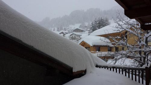 a roof covered in snow next to a house at Family Apartments Le Chalet in Champoluc