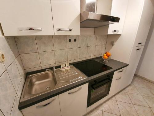 a small kitchen with a sink and a stove at BUCO seafront apartments & fastfood in Pakoštane