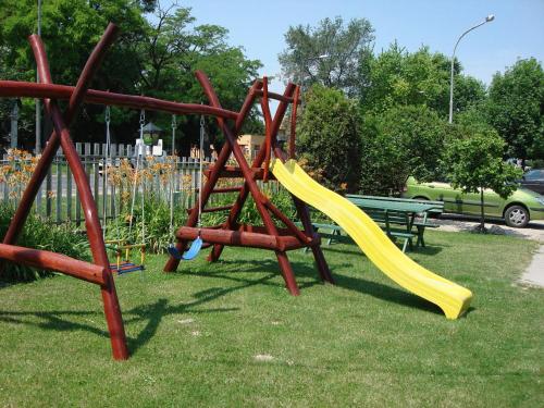 a playground with a yellow slide in a park at Kis-Duna Motel & Camping in Mosonmagyaróvár