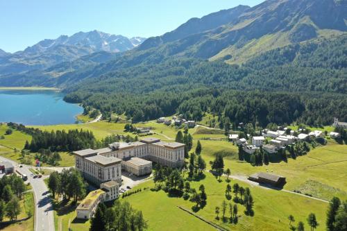 an aerial view of a building with a lake and mountains at Maloja Palace Suites CO2-Neutral in Maloja