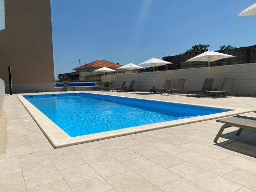 a swimming pool with blue water and chairs and umbrellas at The View Luxury Residence with Pool in Zadar