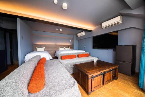 a bedroom with two beds and a couch and a tv at Hotel Brick in Naha