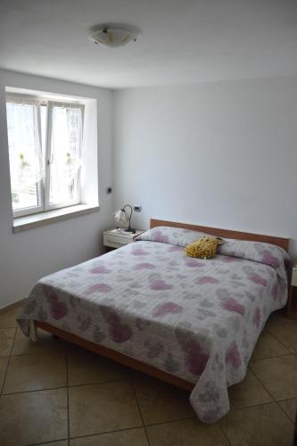 1 dormitorio con 1 cama con edredón morado y 2 ventanas en La Terrazza sul Lago, en Malcesine
