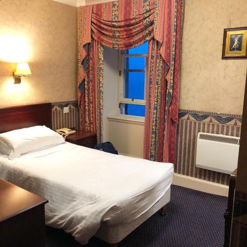 a hotel room with a bed and a window at Queens Hotel in Lerwick