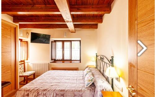 a bedroom with a bed in a room with wooden ceilings at Casa Hortensia in Salas