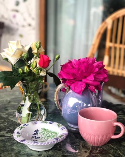 a table with a vase and a cup and flowers at Conacul Paloși in Horezu