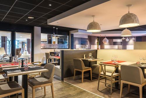 a restaurant with tables and chairs and windows at Holiday Inn Toulouse Airport by IHG in Blagnac
