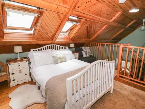 a bedroom with a crib in a room with wooden ceilings at The Barn in Dalbeattie